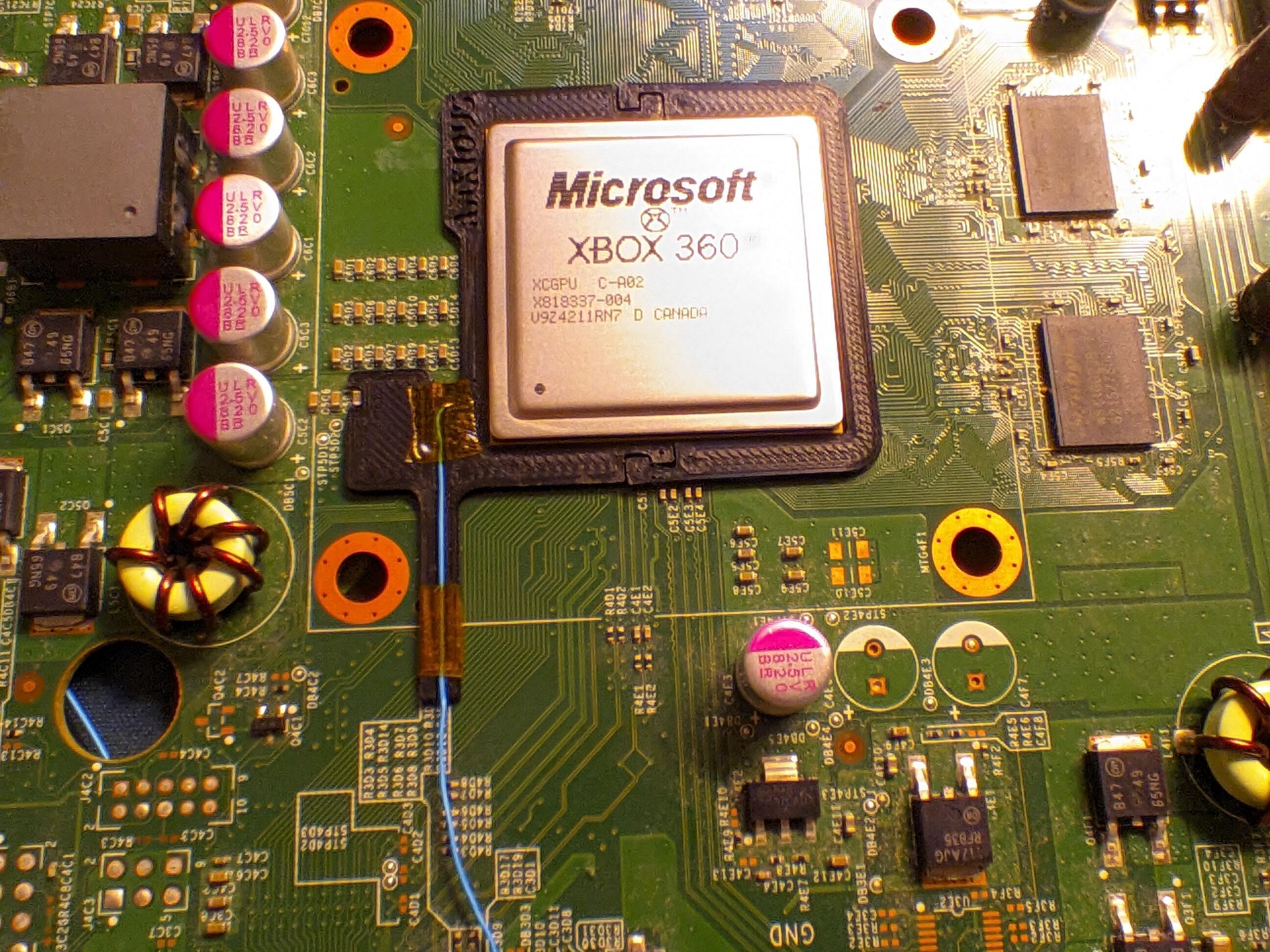 The postfix adapter snuggly fitted around the perimeter of the APU. A blue wire is held within its designated channel on the part with some kapton tape. The wire leads from the edge of the APU to a point out of frame.