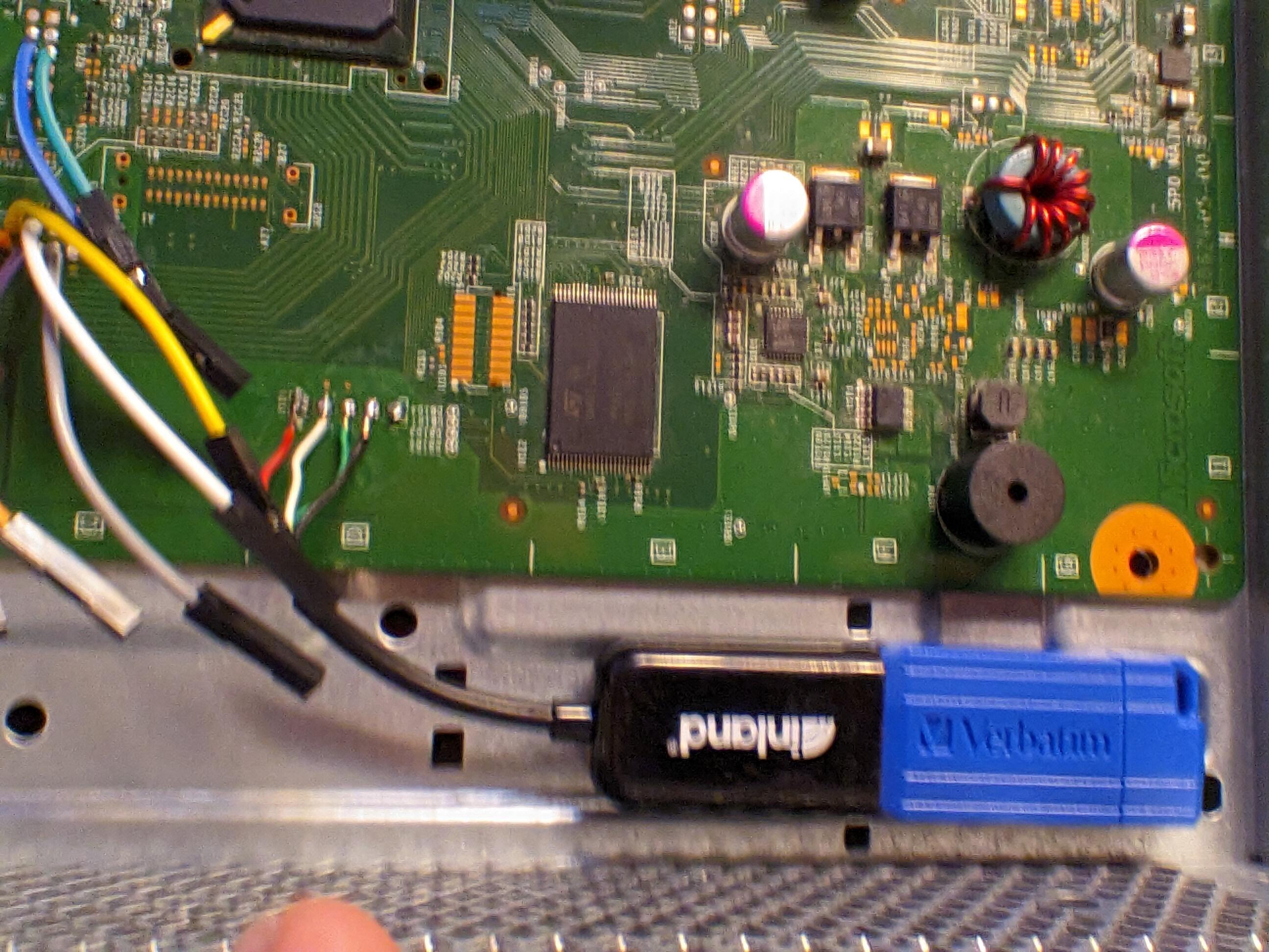 Inland USB-OTG adapter soldered to some points on the top of the board. It sits in a gap in the ESD sheilding that the motherboard sits on. The disk drive will sit right over it when it gets reinstalled. A blue Verbatim brand USB drive is plugged into the new port.