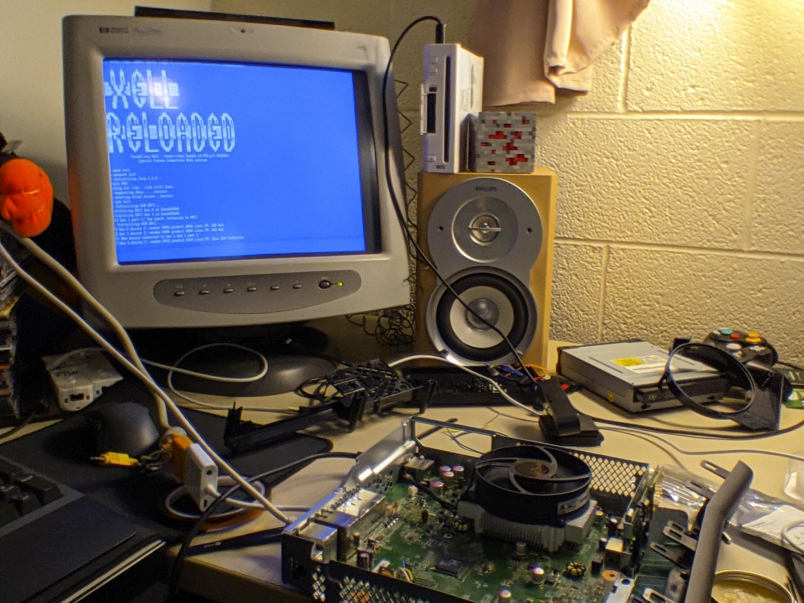 Xbox booted into Xell Reloaded. It shows a blue screen with an Ascii art "XELL RELOADED". Below that is some info about the console and its network connection. It's displayed on an HP CRT display connected with a VGA to HDMI adapter. My desk is very much a mess in this photo.